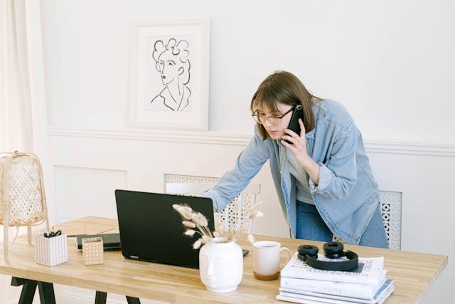 Person talking on the phone and using a laptop